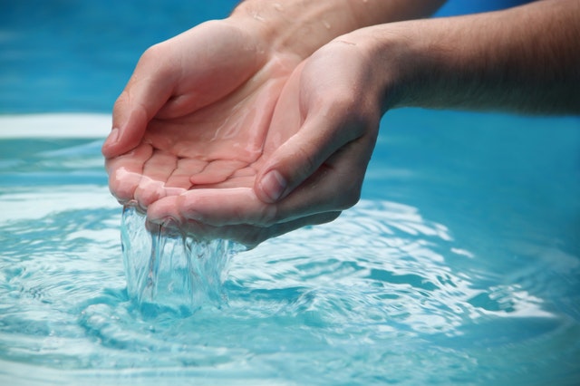 Grafika przedstawiająca dłonie zanurzone w czystej wodzie.